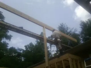 Carpenter setting a ridge beam over a new addition frame — Ice Dam Removal by Roofing Brothers in Agency