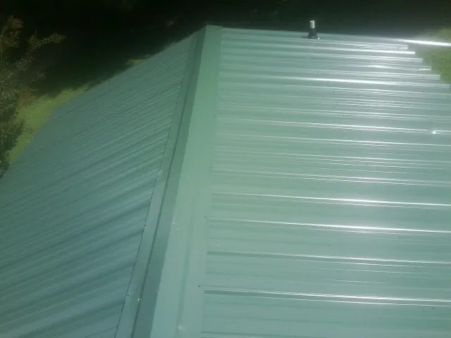 New green metal panels meeting at the ridge of a roof — Flat Roof Repair work by our crew in Agency