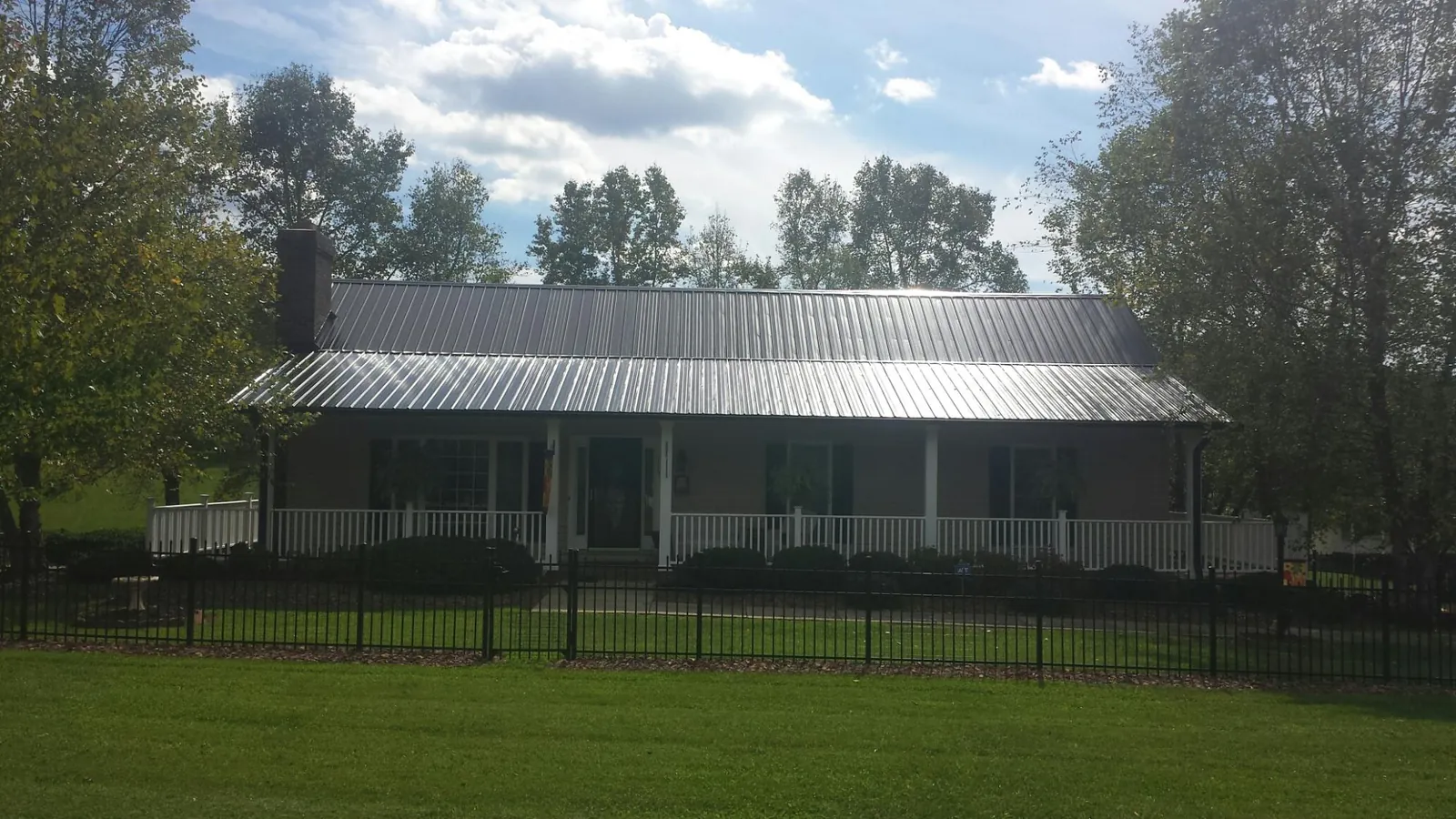 Gray metal roof on a brick ranch with a full width front porch — Gutter Guard Installation work by our crew in Agency