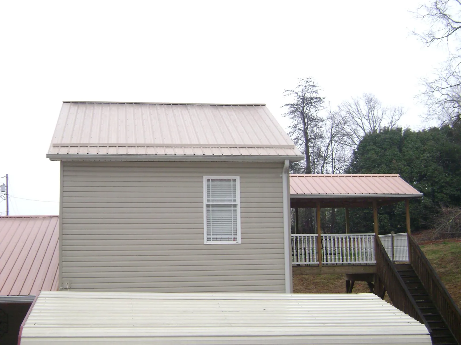 Tan metal roofs on a two story addition and attached porch, from a Roof Replacement job in Agency